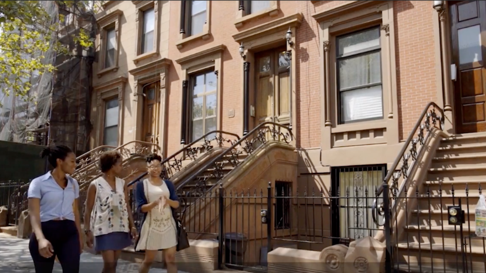 3 young Black people walk down a street in Harlem